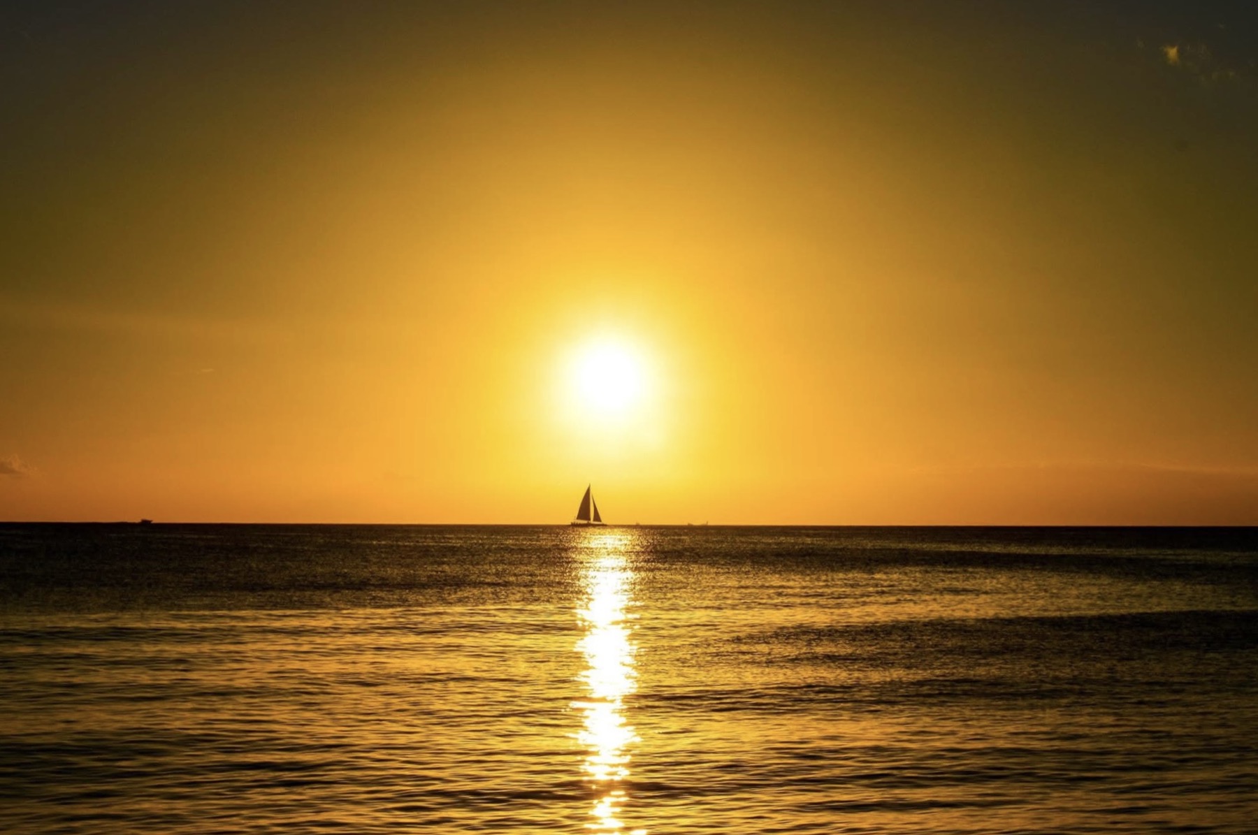 Fotografía de atardecer sobre el mar con un velero
